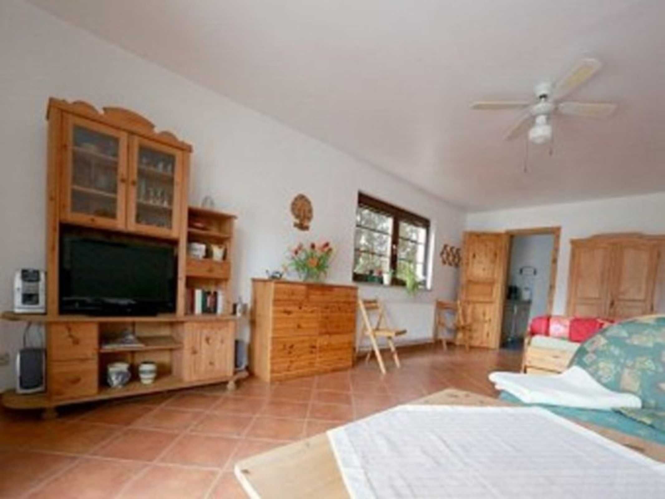 Ein Zimmer mit Holzschrank, Fernseher, Schreibtisch, Stuhl und Bett.