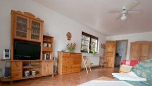 A room with a wooden cabinet, a television, a desk, a chair, and a bed. - Apartment 1 - Apartments family Moll (Benz)