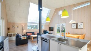 A modern kitchen with a dishwasher, a dining area with a table and chairs, and a living area with a sofa and a TV. - Beautiful home in Ebeltoft with kitchen (Ebeltoft)