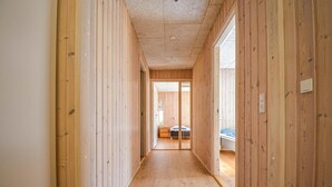 A narrow hallway with wooden walls and a wooden floor, leading to a room with a bed and a window. - Beautiful home in Ebeltoft with kitchen (Ebeltoft)