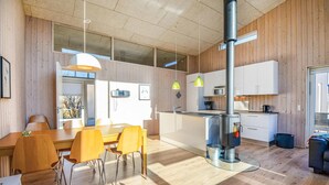 A modern kitchen with wooden walls, a central island, and pendant lighting. - Beautiful home in Ebeltoft with kitchen (Ebeltoft)