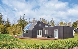 Une maison moderne avec un toit en pente, de grandes fenêtres et un espace patio.