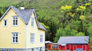 A yellow house with a grey roof and white windows, adjacent to a red barn with a grey roof. - Pet friendly home in Eidfjord with WiFi (Eidfjord)