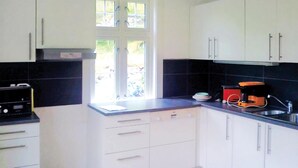 A compact kitchen with white cabinets, a black countertop, a coffee maker, and a window providing natural light. - Pet friendly home in Eidfjord with WiFi (Eidfjord)