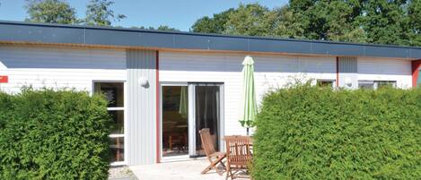 Een modern gebouw met een overdekte patio, compleet met een tafel, stoelen en een grote parasol.