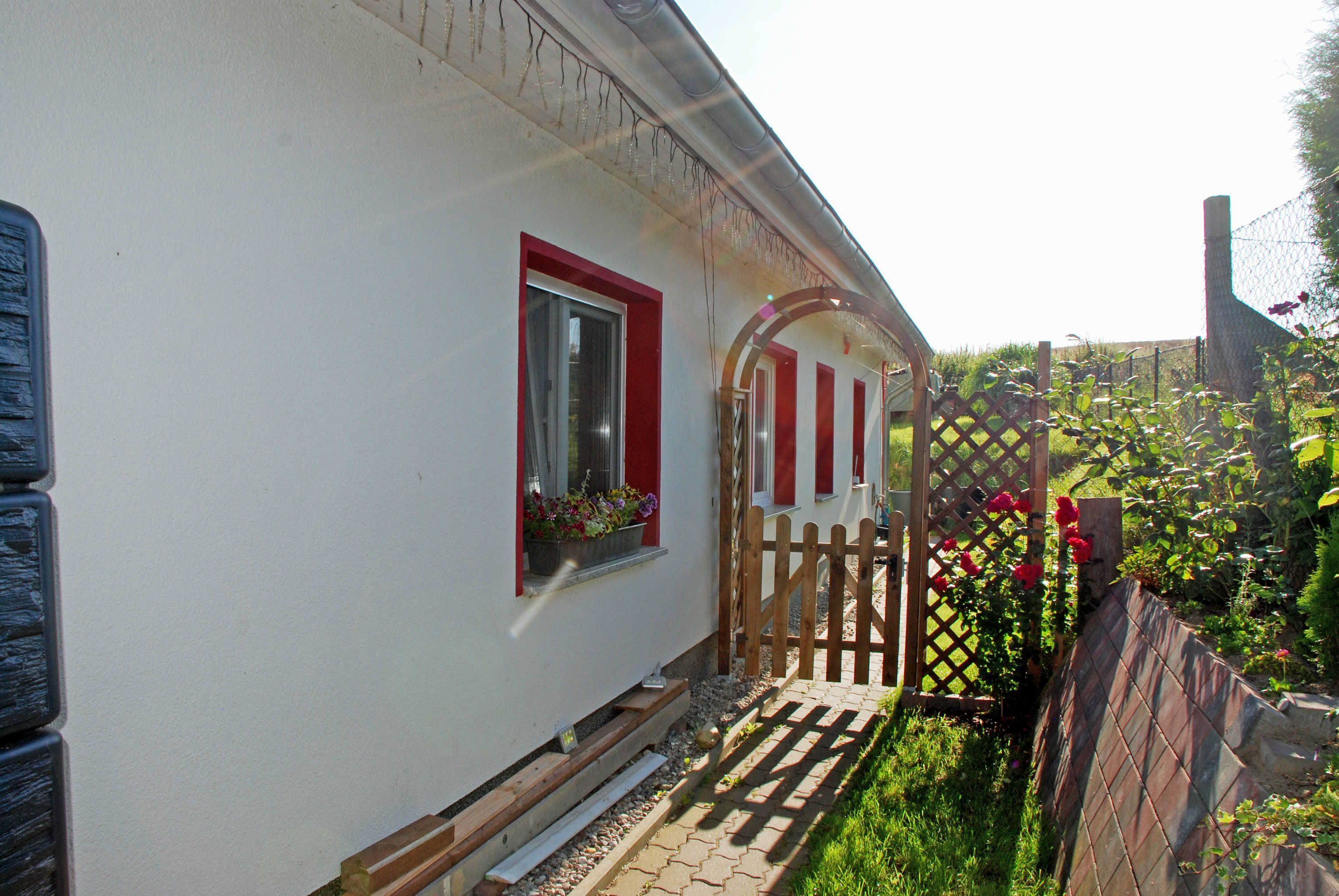 A white building with red window frames and a wooden gate.