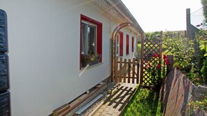 Un edificio blanco con marcos de ventana rojos y una puerta de madera.