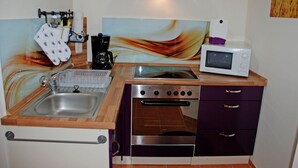 Una cocina compacta con pileta, estufa, horno, microondas y un original revestimiento.