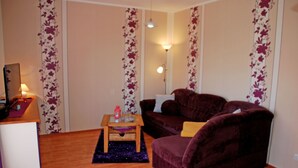 Una sala de estar con un sofá morado, una mesita de madera y una lámpara.