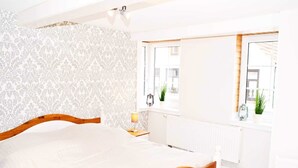 A bedroom with a bed, a window with a view, a radiator, and a nightstand with a lamp. - Apartment East - Family Jansen - Home sweet home (Maasholm)