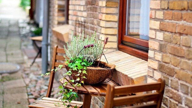 A wooden table and chairs outside a brick building with a window. - Apartment East - Family Jansen - Home sweet home (Maasholm)