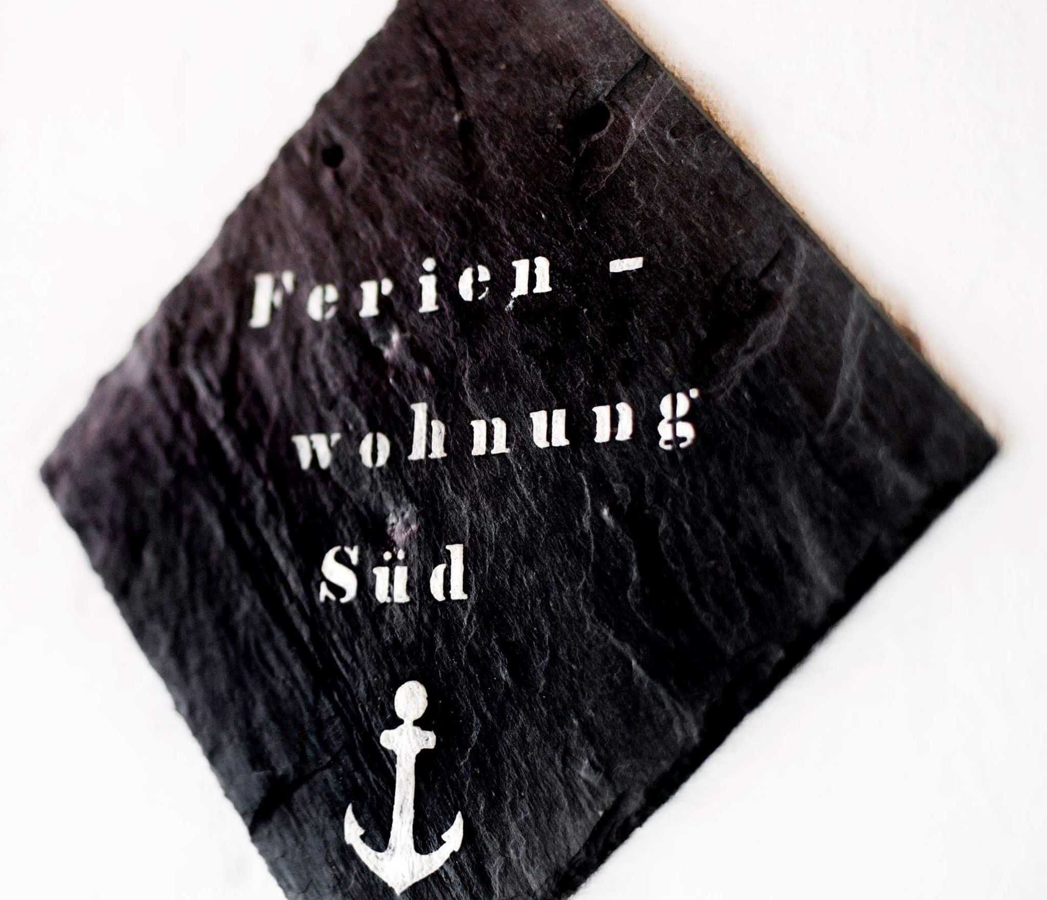 Une surface noire texturée avec du texte blanc et un symbole d’ancre.
