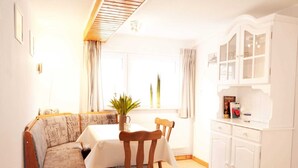 A dining area with a wooden table and chairs, a sofa, and a cabinet with glass doors. - Apartment East - Family Jansen - Home sweet home (Maasholm)
