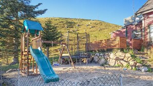 A playground with a slide and swings, surrounded by a stone wall and a wooden fence. - Nice apartment in Sandnes with WiFi (Sandnes)