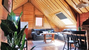 A cozy attic room with a wooden sloped ceiling, a black leather sofa, a wooden coffee table, and a dining table with chairs. - Nice apartment in Sandnes with WiFi (Sandnes)