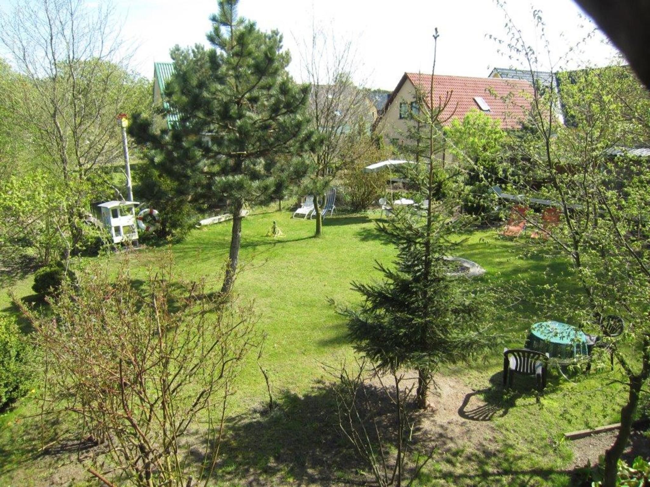 A residential area with a well-maintained lawn, a small gazebo, and a house with a red roof.