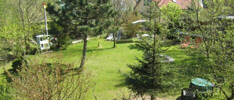 A residential area with a well-maintained lawn, a small gazebo, and a house with a red roof.