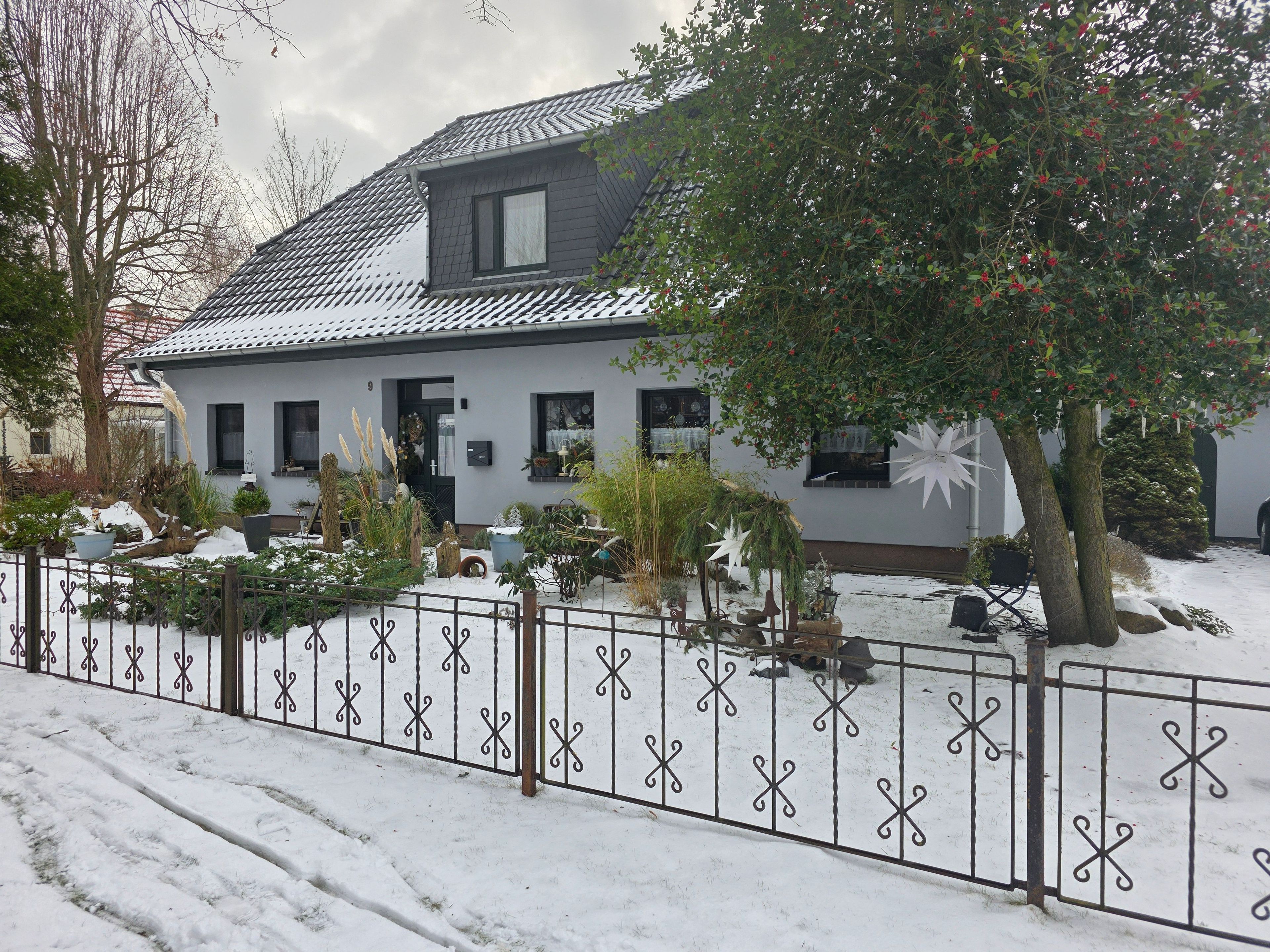 A house with a grey roof, a white exterior, and a snow-covered yard.