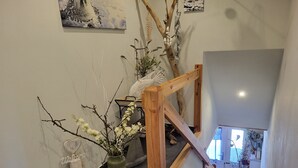 A wooden staircase with a rustic design, a vase with flowers, and a welcome sign on the wall. - Blue Water 2, Germany (Wustrow)