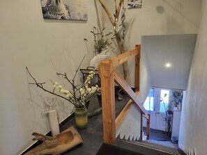 Una escalera de madera con diseño rústico, un jarrón con flores y un letrero de bienvenida en la pared.