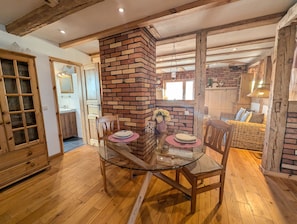 A dining area with a glass table, wooden chairs, a brick fireplace, and a wooden ceiling. - Blue Water 2, Germany (Wustrow)