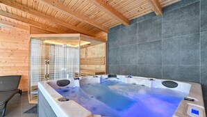 Een moderne badkamer met een ruim bubbelbad, houten wanden en een douchecabine van glas.