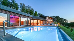 Een modern huis met een zwembad, grote ramen en een verzorgd gazon.