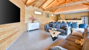 Een modern ingerichte blokhut met woonkamer, eethoek en keuken.
