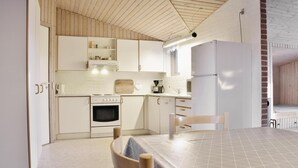 A kitchen with white cabinets, a stove, a refrigerator, and a dining table with chairs. - Nice home in Ringkøbing with sauna (Ringkøbing)