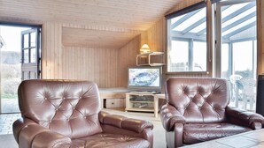 A cozy room with two leather armchairs, a television, and a wooden interior. - Nice home in Ringkøbing with sauna (Ringkøbing)