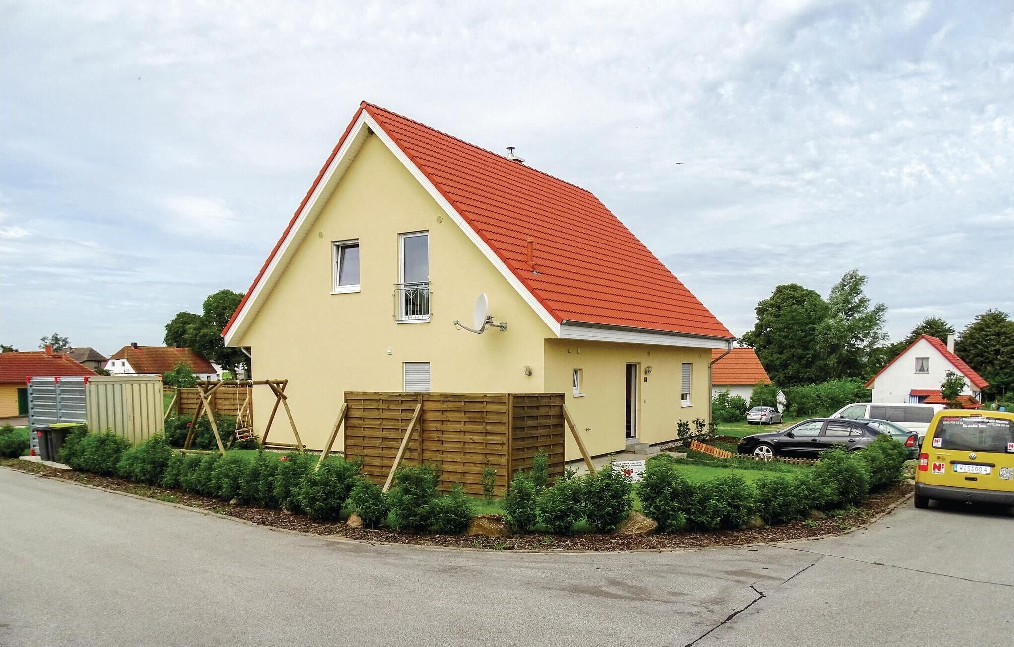 A two-story house with a red roof, a small front porch, and a garage.