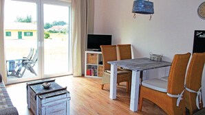 A room with a wooden table, wicker chairs, a television, and a sliding glass door leading to an outdoor area. - Nice apartment in Boiensdorf with WiFi (Boiensdorf)