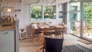 Un intérieur en bois comprenant une table à manger, des chaises et un coin cuisine.