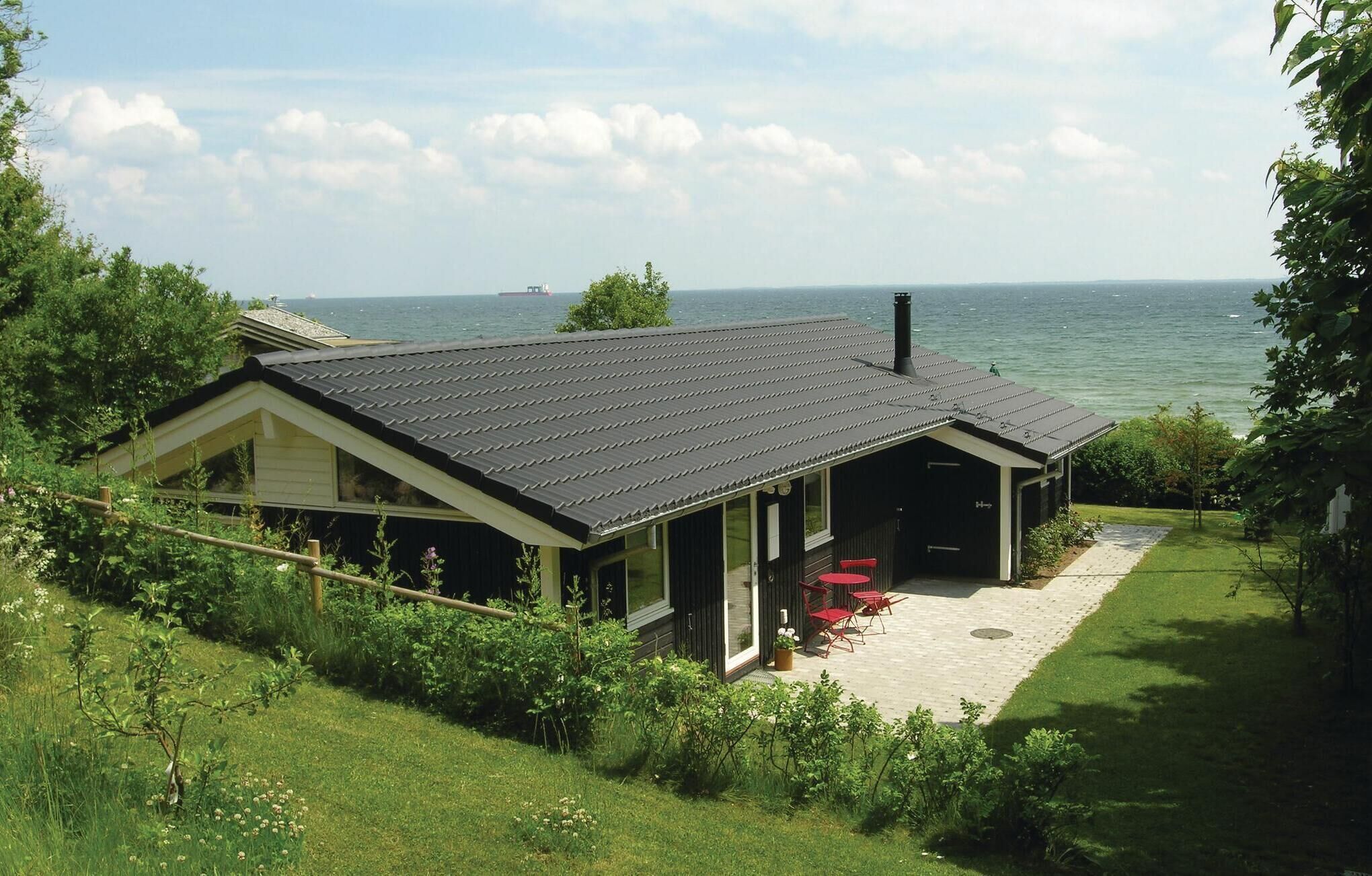 A house with a large deck, a covered porch, and a view of the sea.