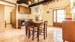 A kitchen with wooden cabinets, a tiled floor, and a dining table with chairs. - Nice home in Castiglione d.Lago PG (Castiglione d.Lago PG)