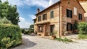A two-story stone house with a gravel driveway, green shutters, and a small balcony. - Nice home in Castiglione d.Lago PG (Castiglione d.Lago PG)