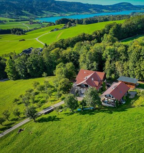 Vista aérea de una propiedad rural con dos edificios principales, un campo extenso y un lago al fondo.