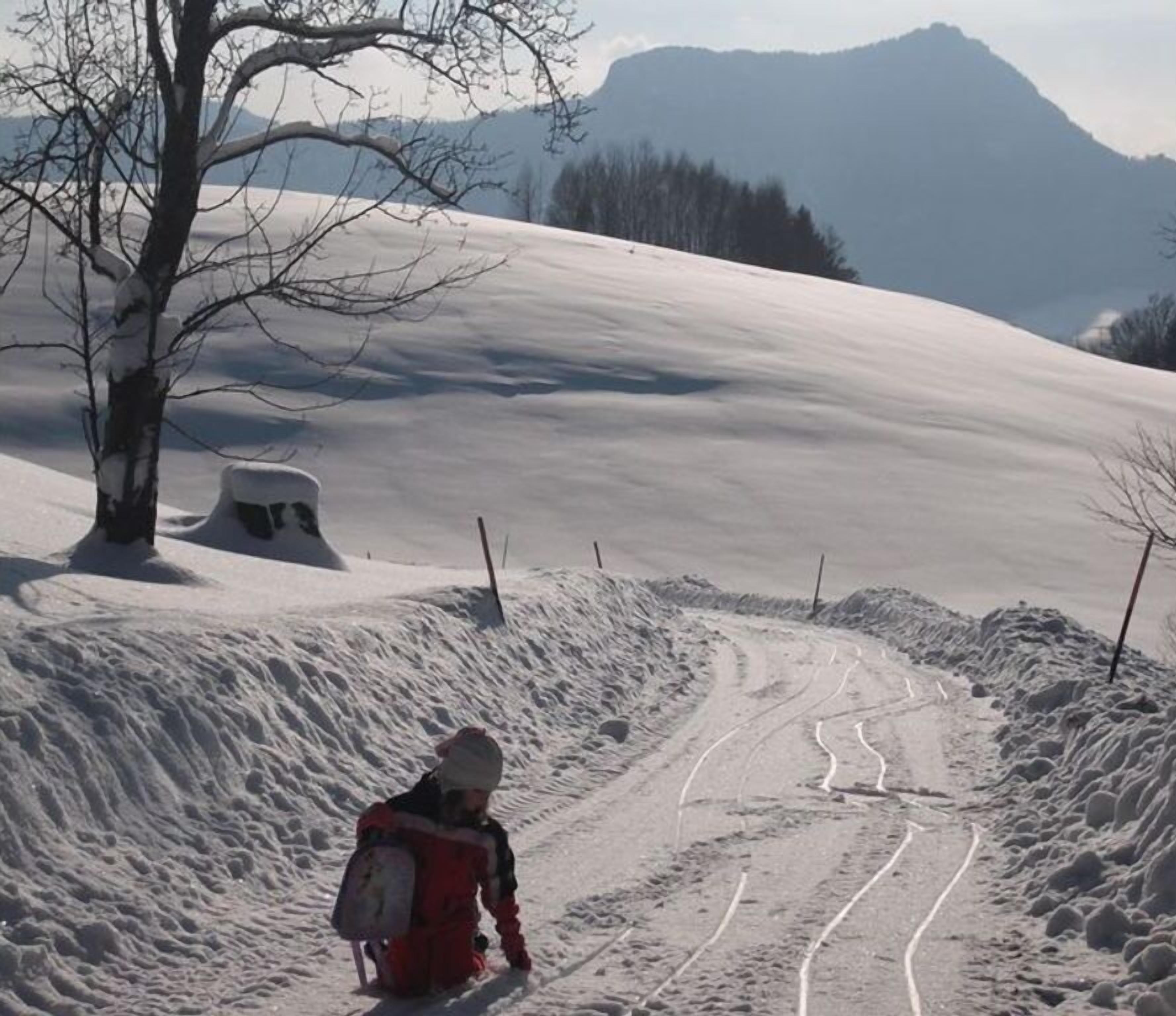 Een besneeuwde bergpad met een persoon in rood en zwart