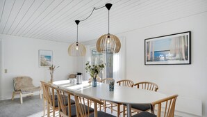 Un espace de salle à manger moderne avec une table ronde, des chaises en bois et des luminaires suspendus.