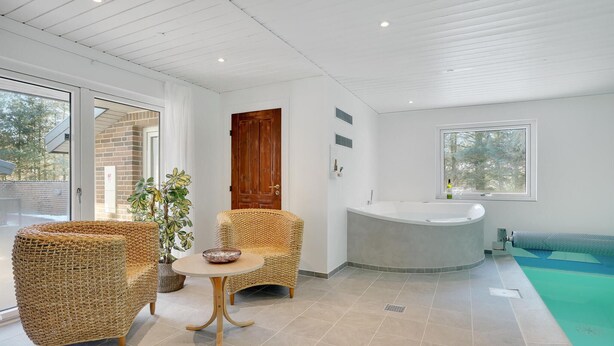 Une salle de bain moderne avec une baignoire sur pieds, des meubles en osier et une plante en pot.