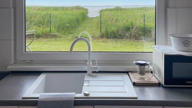 Uma cozinha com vista para um campo gramado e água.