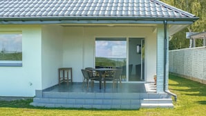 Uma casa com alpendre coberto, mesa de jantar com cadeiras e vista para a paisagem.