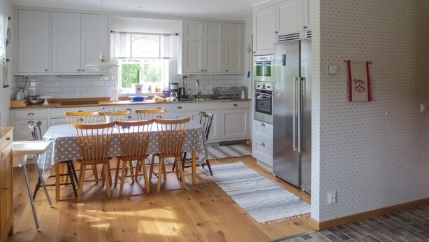 A kitchen with white cabinets, a dining table with chairs, a refrigerator, and a window with curtains. - 4 bedroom beautiful home in Gnosjö (Gnosjö)