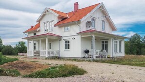 A two-story white house with a red-tiled roof, a porch with chairs, and a satellite dish. - 4 bedroom beautiful home in Gnosjö (Gnosjö)