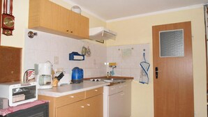 Eine kleine Küche mit Holzschränken, einer weißen Arbeitsplatte, einem eingebauten Backofen und einem kleinen Kühlschrank.