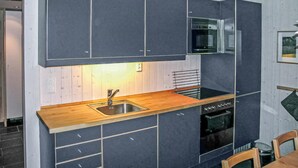 Una cucina compatta con mobili scuri, un piano di lavoro in legno, un lavandino in acciaio inossidabile e un forno integrato.