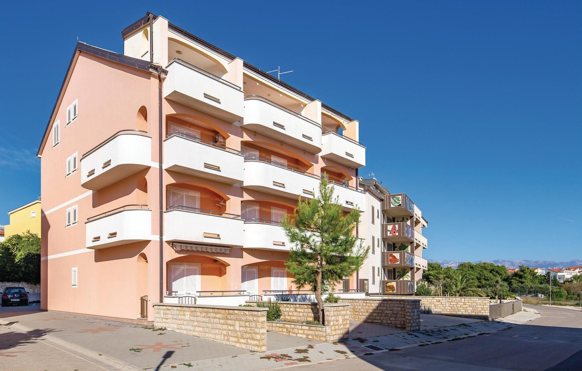 A multi-story residential building with balconies, a stone facade, and a clear sky.