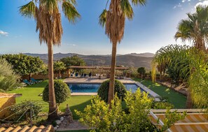 Un espace piscine doté de chaises longues, d’une pergola et offrant une vue sur les montagnes.