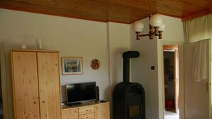 Una sala de estar con televisor, aparador de madera y estufa a leña.