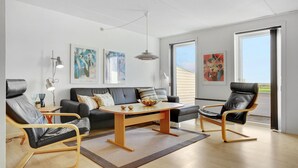A modern living room with a black leather sofa, two leather armchairs, a wooden coffee table, and artwork on the walls. - 3 bedroom lovely apartment in Rømø (Rømø)